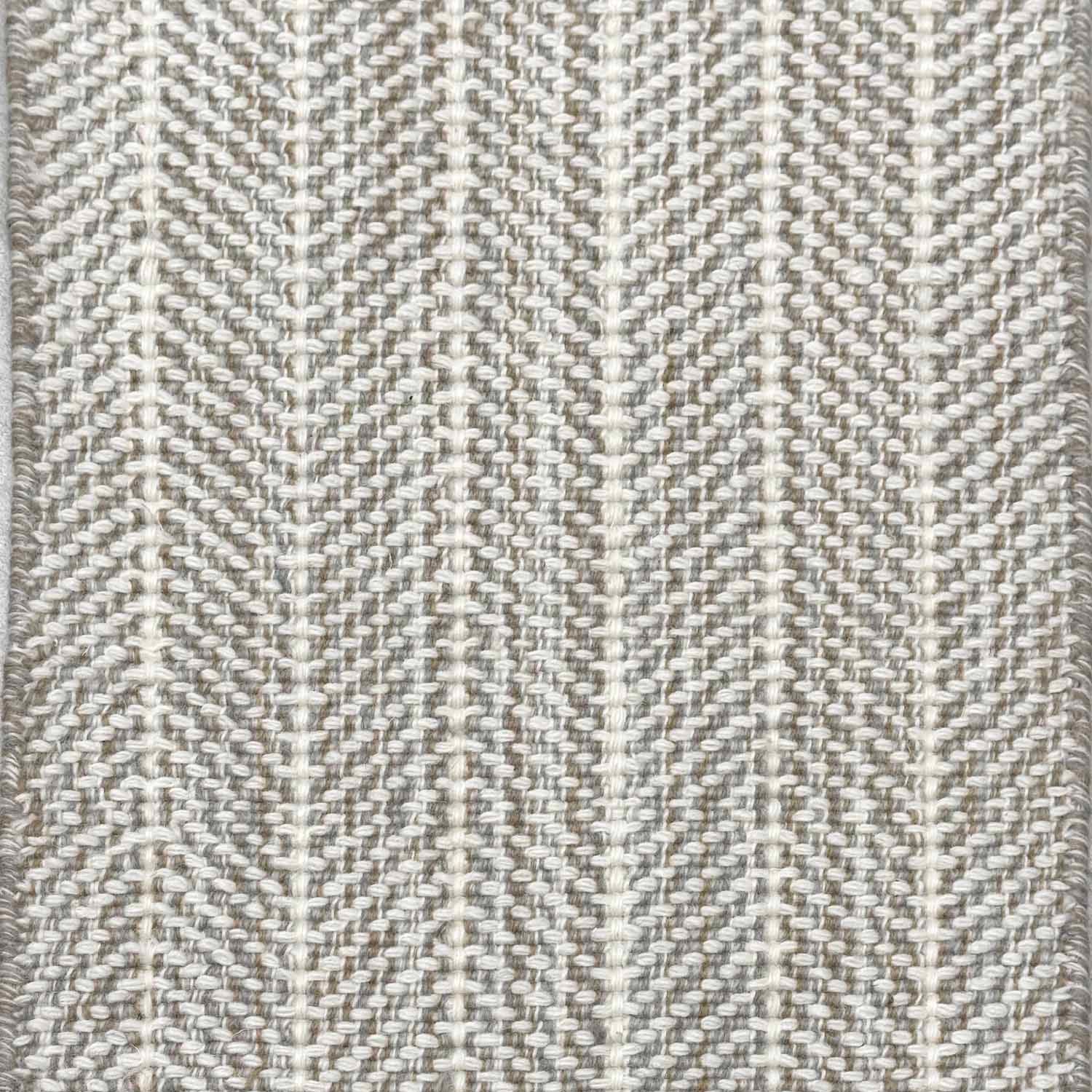Close up of broadloom carpet with striated herringbone weave in white with accents of grey and taupe.