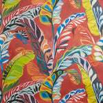 Close up of wallpaper with expressive painterly banana-leaf pattern in red, yellow, green, pink and blue on a red field. 