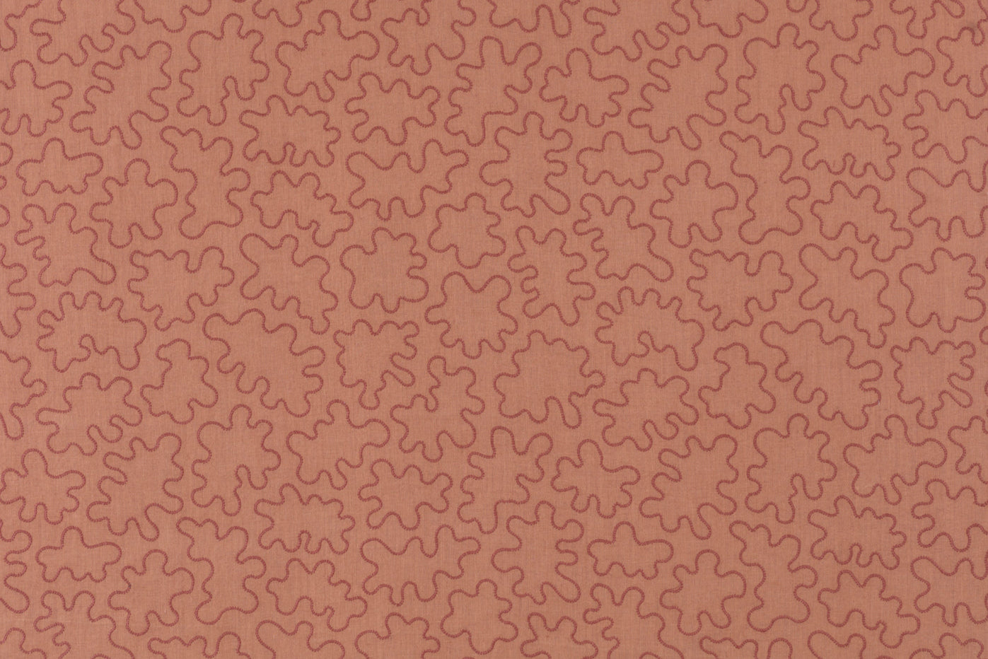 Fabric with an abstract embroidered pattern in clay pink on a clay pink field.