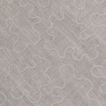 Fabric with an abstract embroidered pattern in white on a cream field.