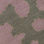Detail of a handwoven rug in an abstract coral design grey and purple with a tan accent line. 