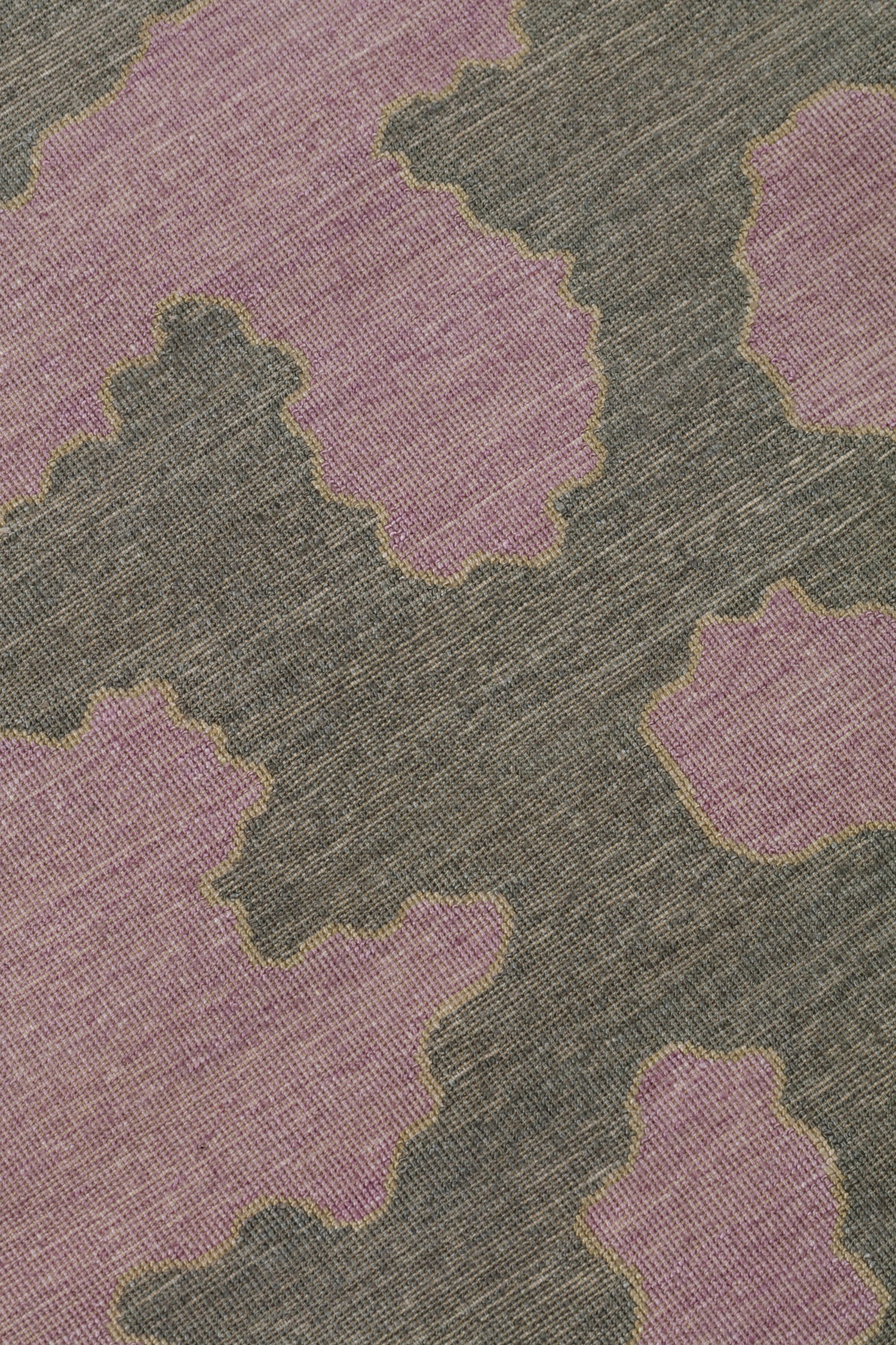 Detail of a handwoven rug in an abstract coral design grey and purple with a tan accent line. 