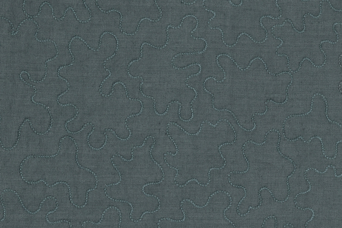 Detail of fabric with an abstract embroidered pattern in gray on a gray field.