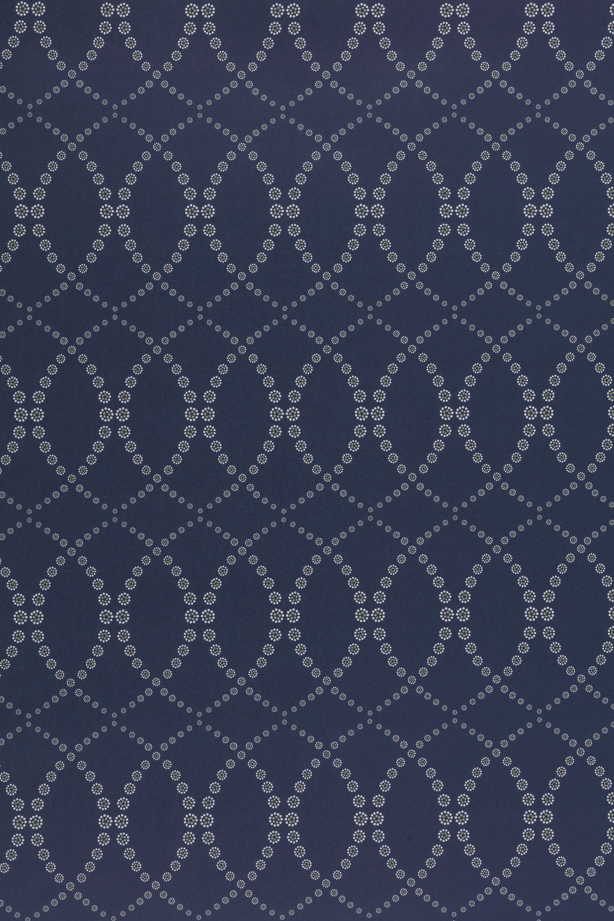Wallpaper in a playful floral lattice print in white and tan on a navy blue field.