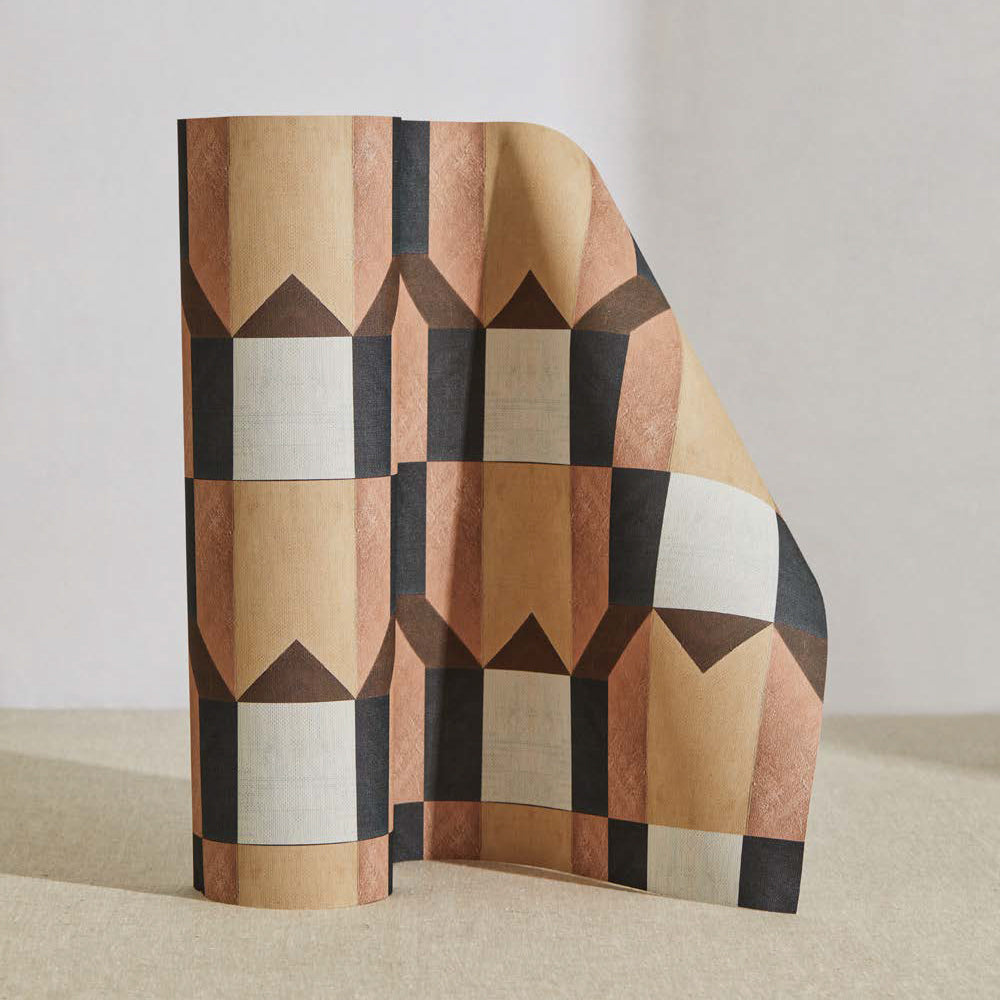 A curved partition stands on the ground, covered in a geometric grid print in pink, brown, gray and white.