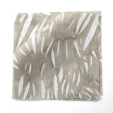 Fabric swatches in an abstract leaf pattern in white on a taupe grey watercolor field.