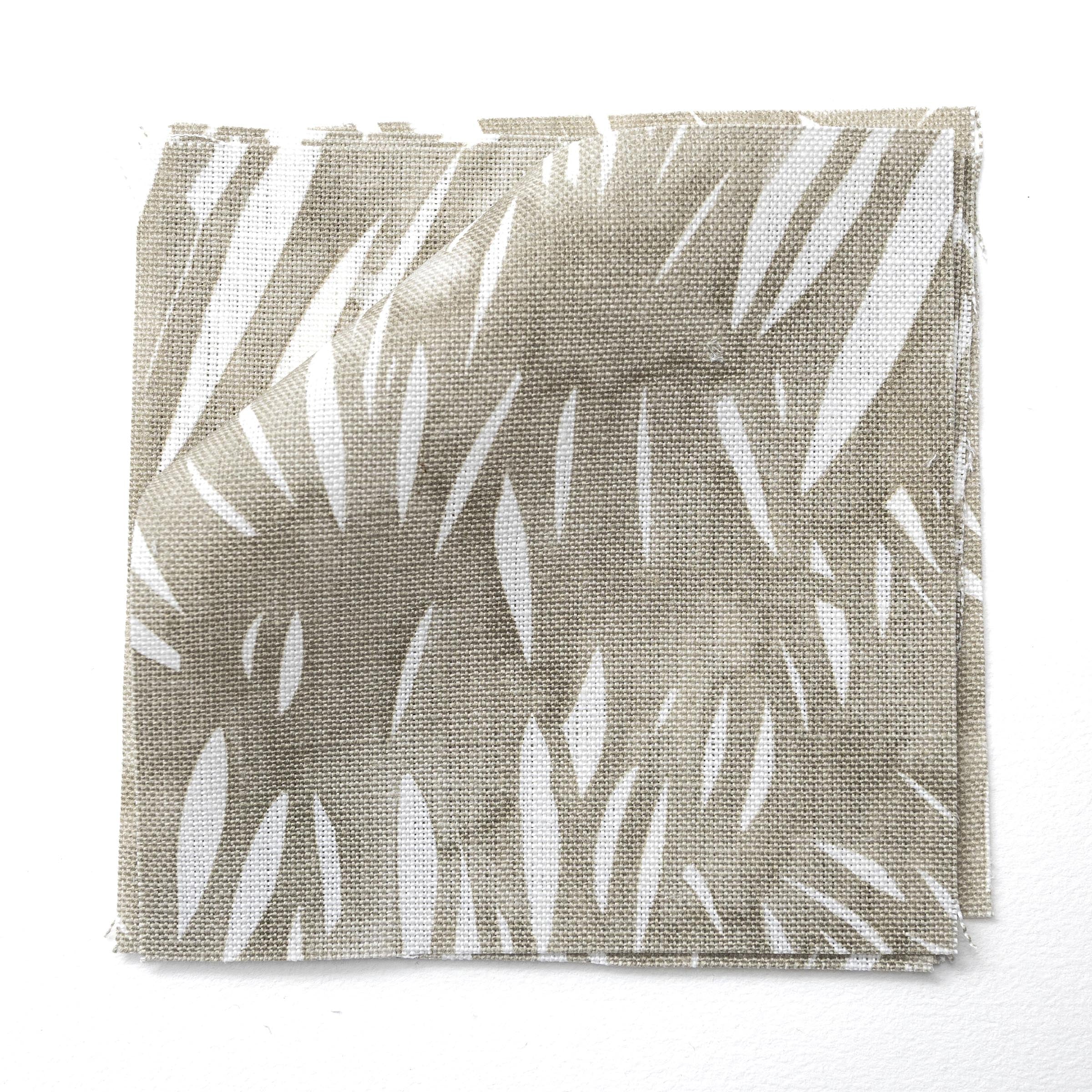 Fabric swatches in an abstract leaf pattern in white on a taupe grey watercolor field.