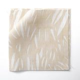 Fabric swatches in an abstract leaf pattern in white on a pale yellow watercolor field.
