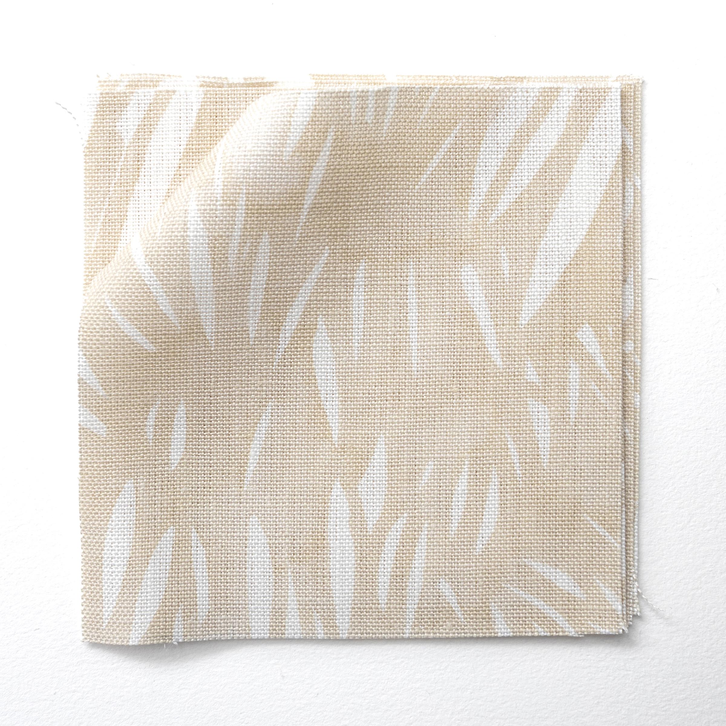 Fabric swatches in an abstract leaf pattern in white on a pale yellow watercolor field.