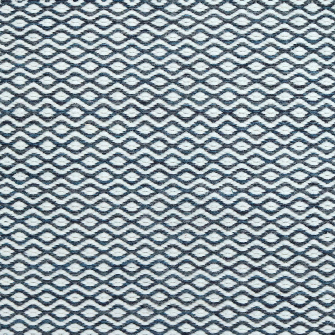 Flatweave rug in a small scale zigzag dot stripe in cream on a navy blue field.