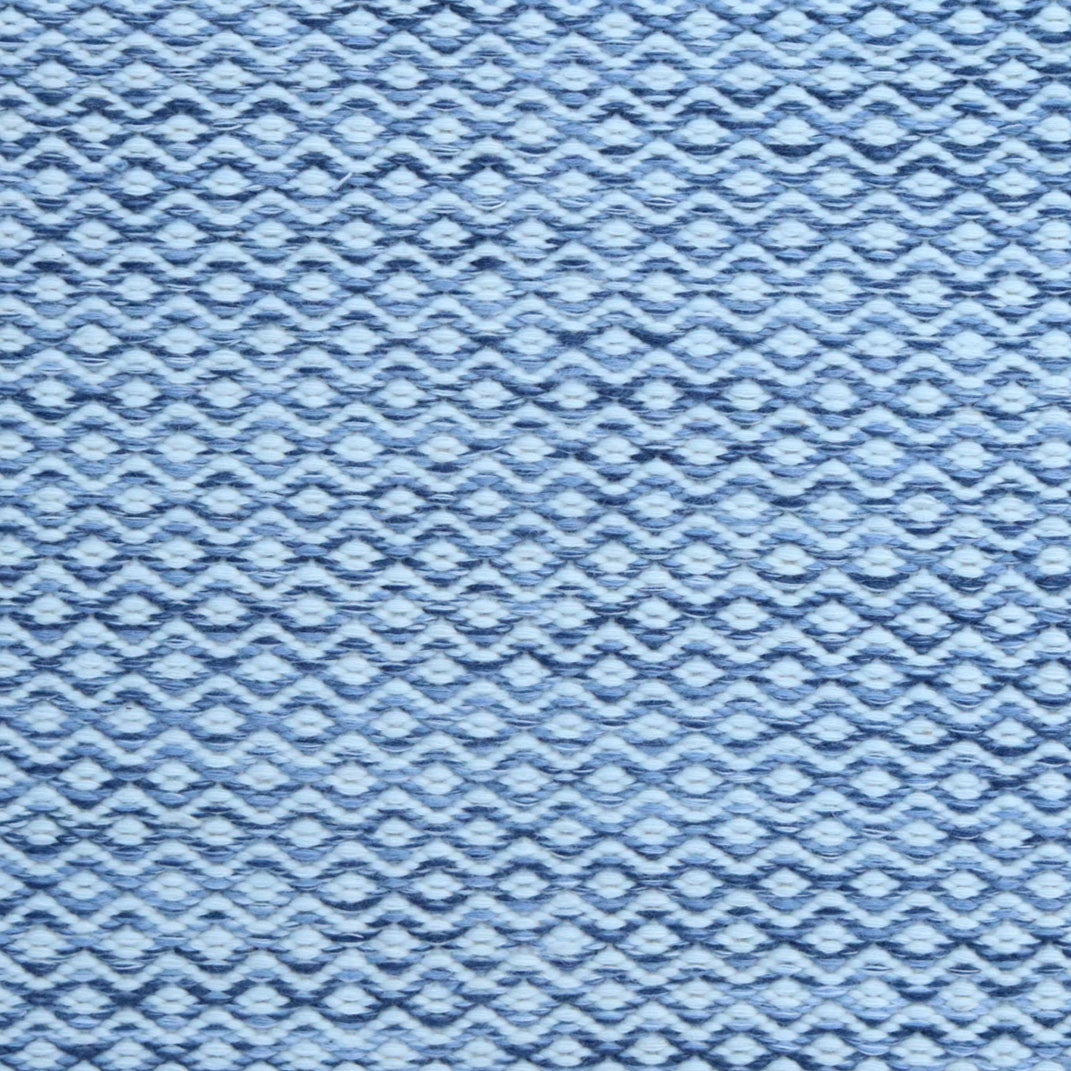 Flatweave rug in a small scale zigzag dot stripe in cream on a heather blue field.