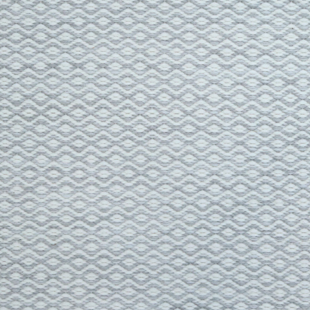 Flatweave rug in a small scale zigzag dot stripe in cream on a light grey field.