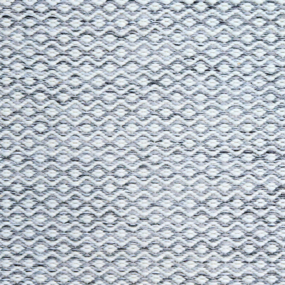 Flatweave rug in a small scale zigzag dot stripe in cream on a heather charcoal field.