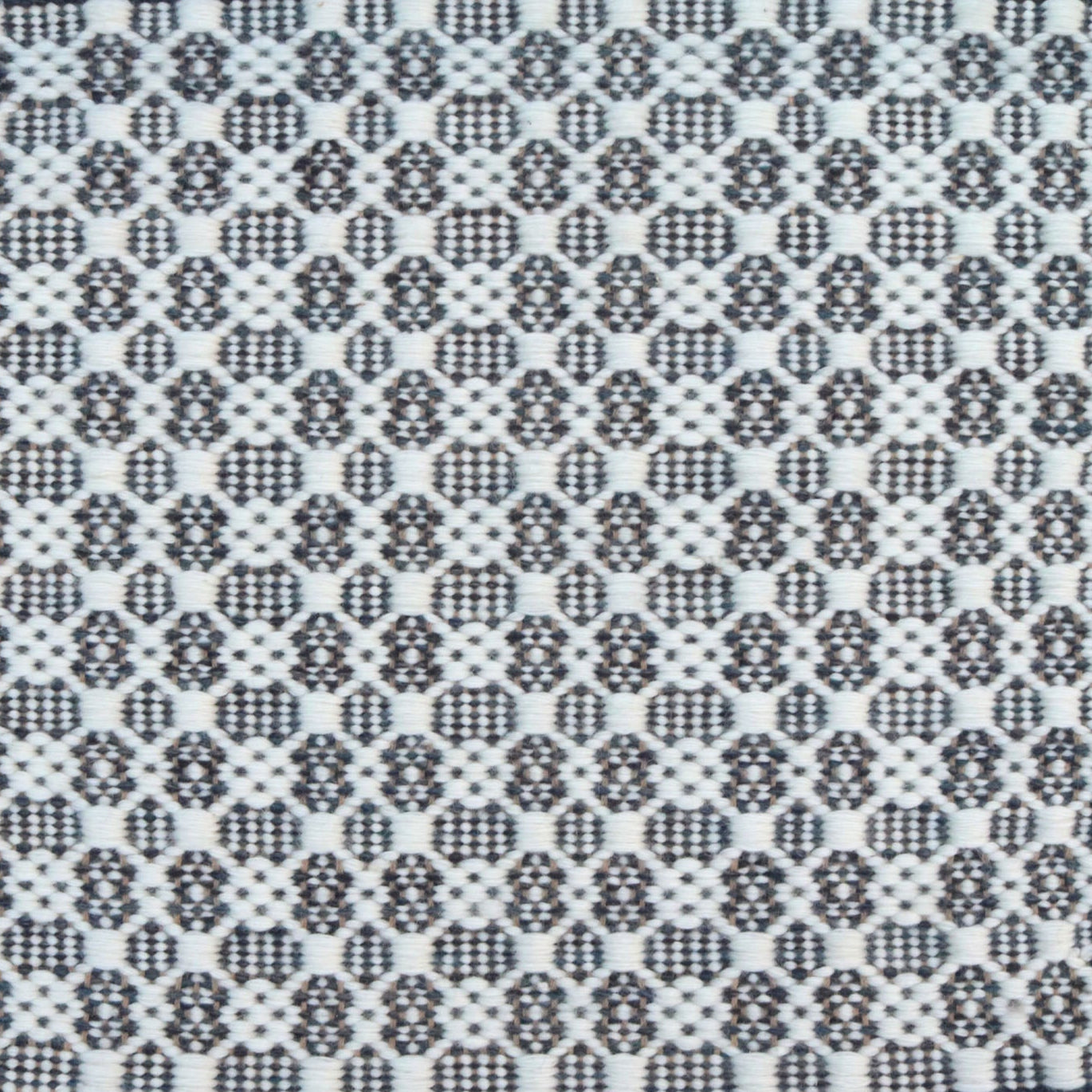 Flatweave rug in a small scale decorative lattice design in cream on a dark grey field. 