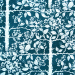 Detail of wallpaper in a large-scale tree and leaf print in white on an indigo field.