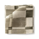 Stacked swatches of fabric in a large-scale checked pattern in shades of olive green and cream. 