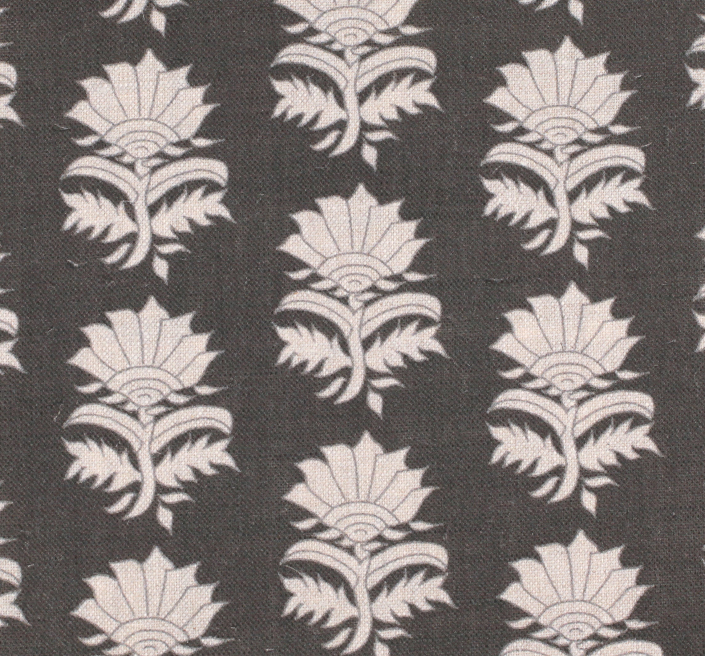 Detail of fabric in a repeating thistle print in cream and gray on a charcoal field.