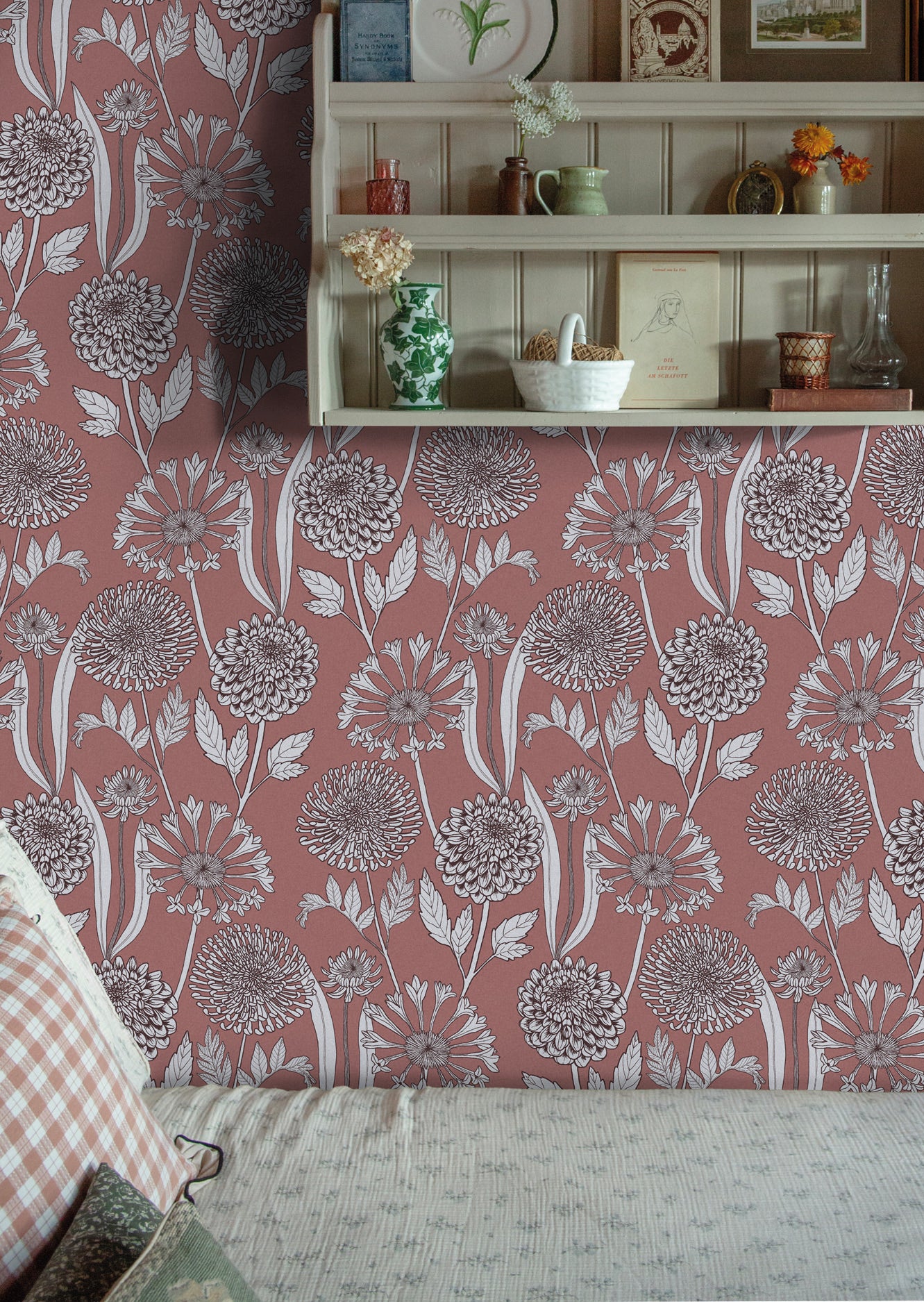 Cozy reading nook with a decorative wooden shelf against a pink floral wallpaper. 
