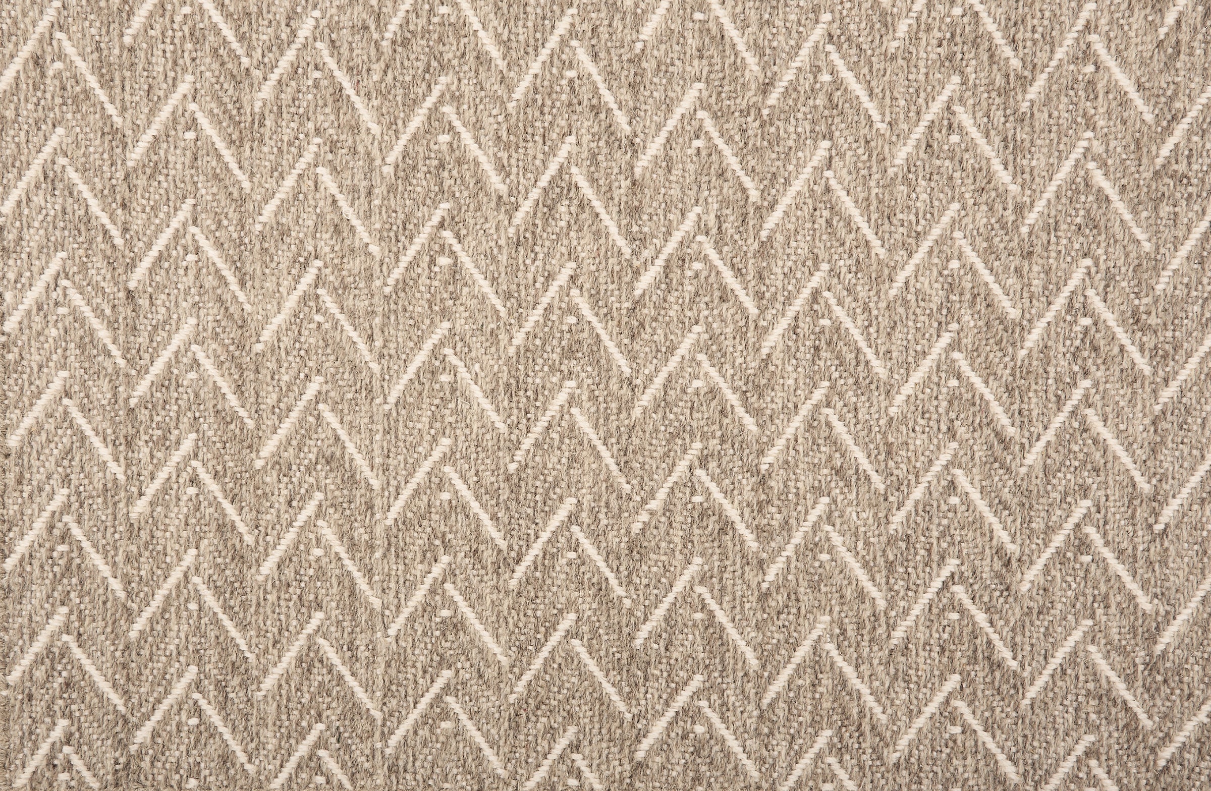 Broadloom carpet in a herringbone pattern in heathered taupe with cream accents.