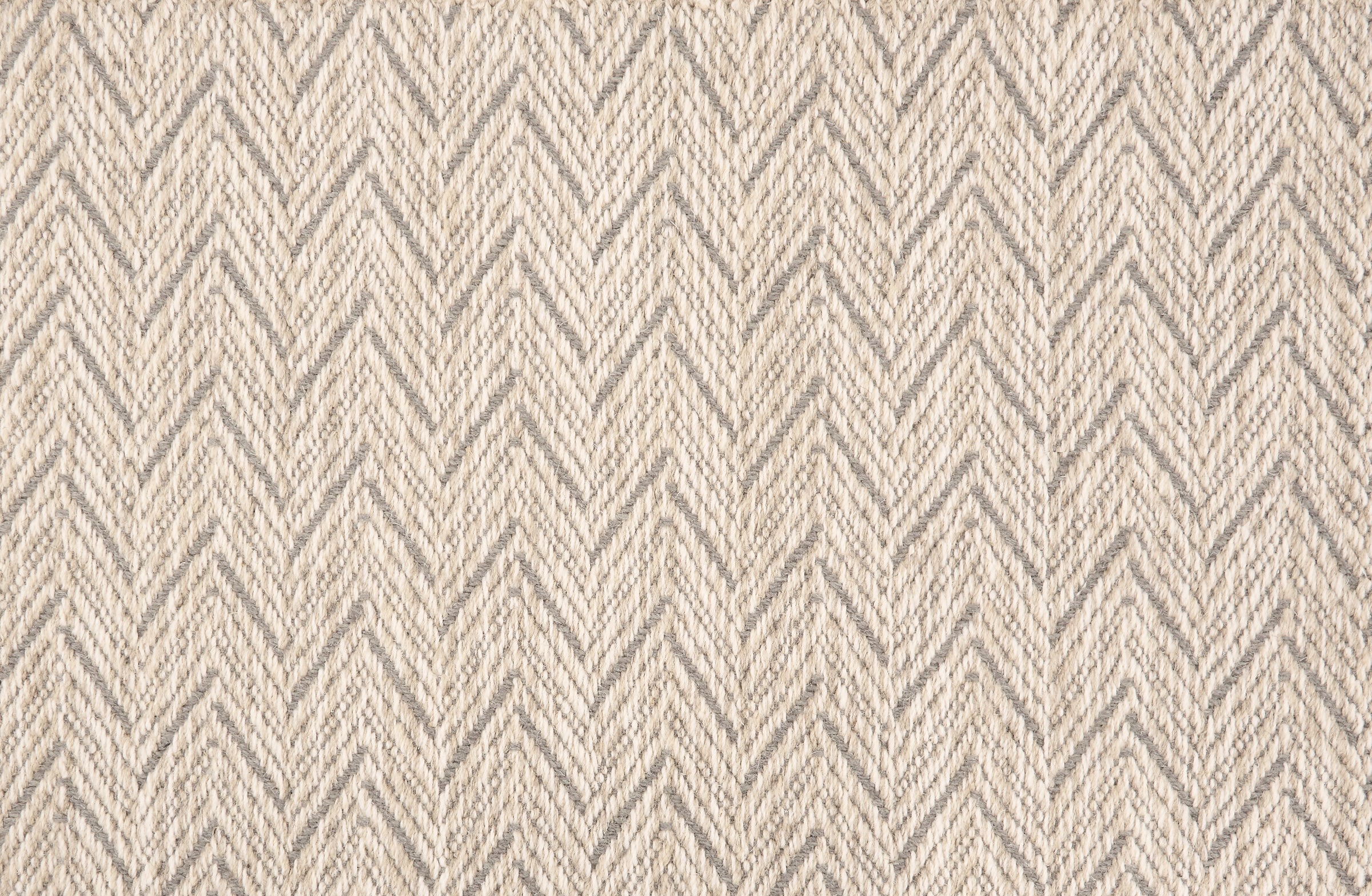 Broadloom carpet in a herringbone pattern in beige with grey accents.