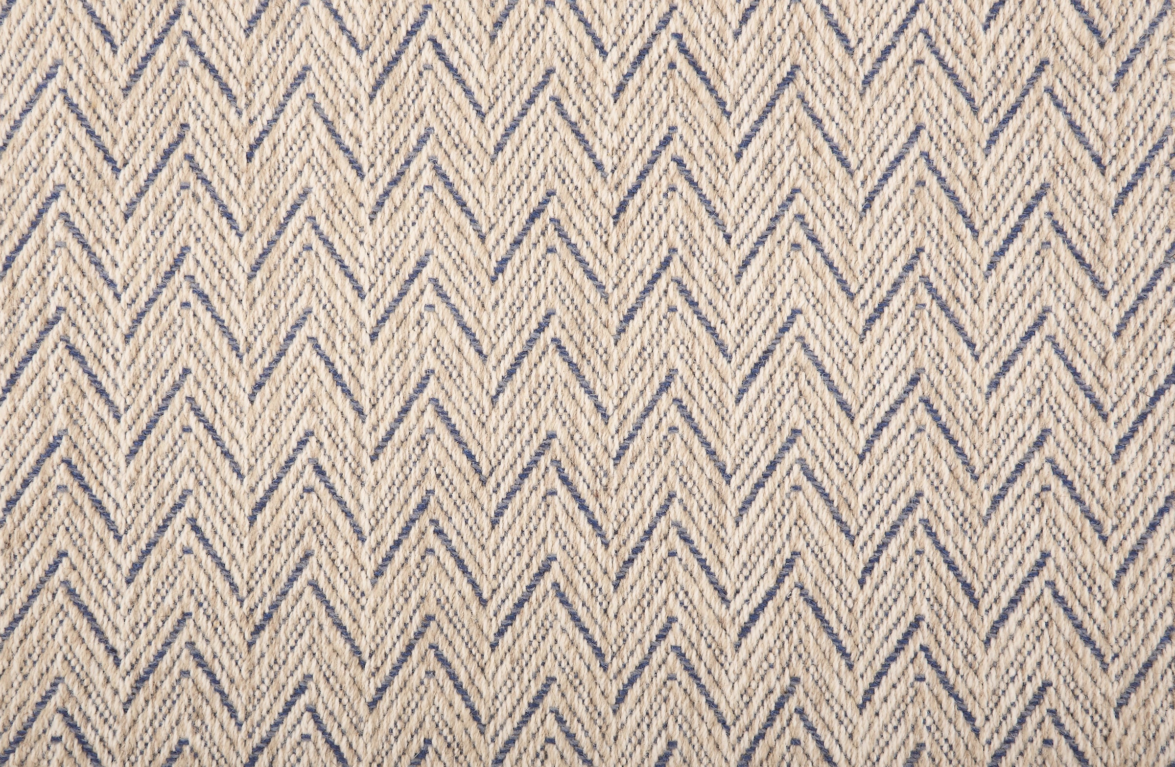 Broadloom carpet in a herringbone pattern in cream with blue accents.