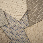 Stack of broadloom carpet samples in a herringbone pattern in array of neutral colors.