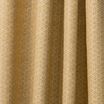 Draped printed fabric in a detailed geometric pattern in white on a goldenrod field.