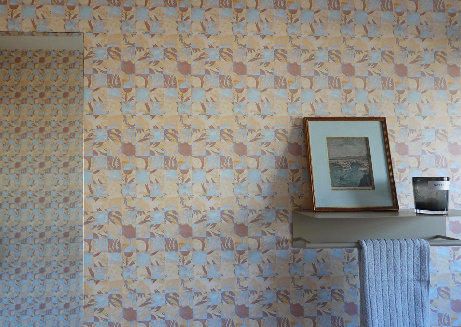 Tropical Check patterned wallpaper with a framed picture and towel on a shelf.