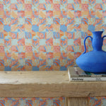 Colorful geometric tropical patterned wallpaper with a blue vase on a wooden surface.