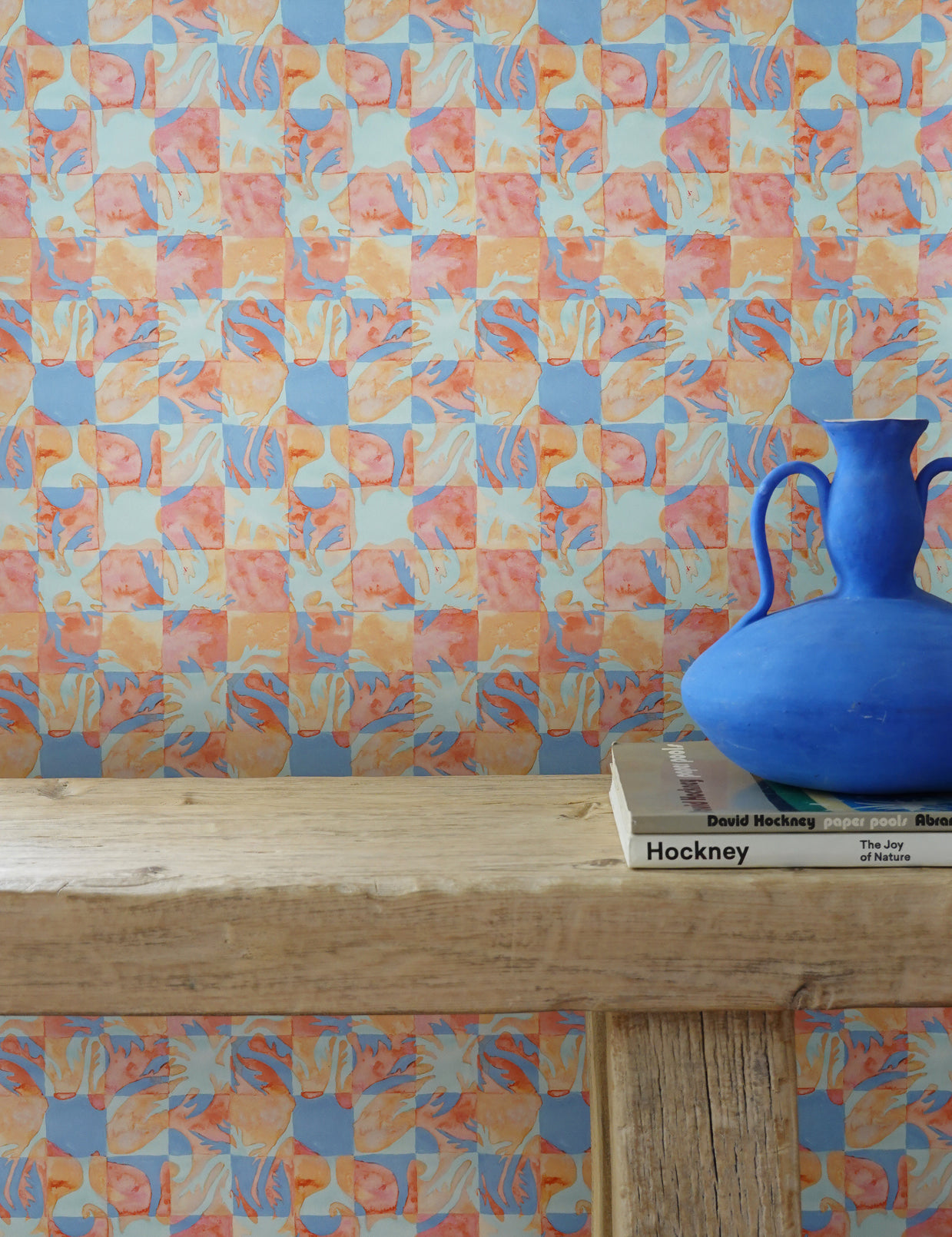 Colorful geometric tropical patterned wallpaper with a blue vase on a wooden surface.