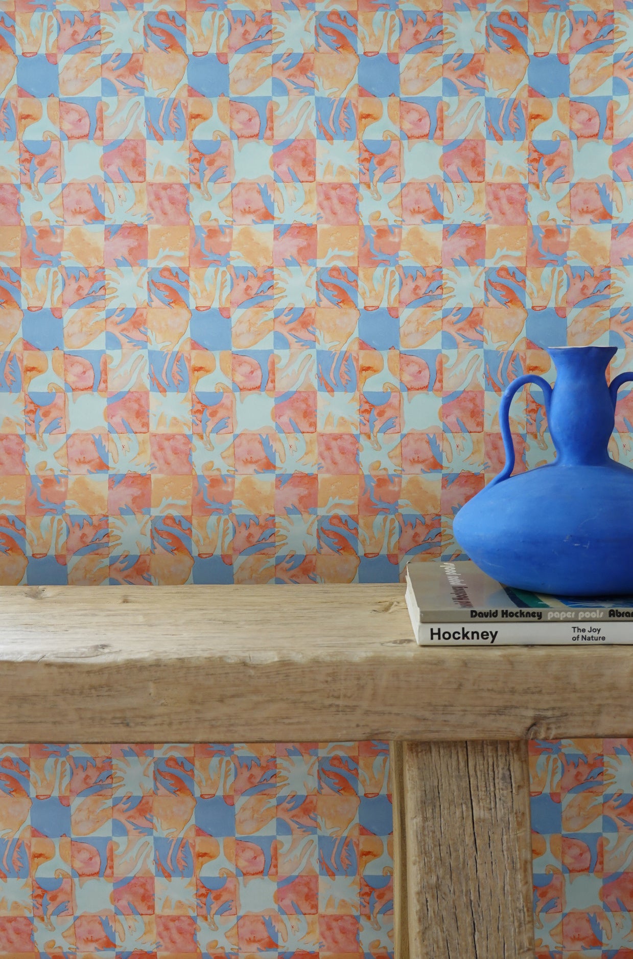Colorful geometric tropical patterned wallpaper with a blue vase on a wooden surface.