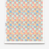 Roll of wallpaper in painterly tropical checkerboard design in blue, coral and orange. 