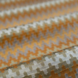 Close-up of fabric with a zigzag pattern in orange, beige, and brown.