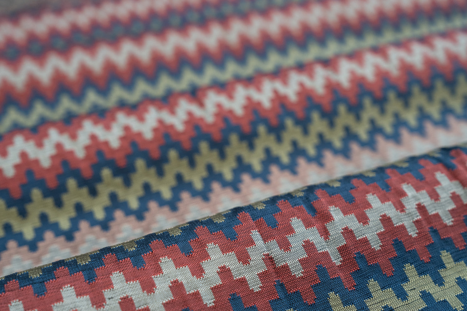 Close-up of fabric with zigzag and houndstooth patterns in red, blue, and green.