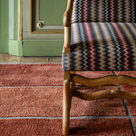 Chair with patterned fabric on a red carpet in a room with green walls.