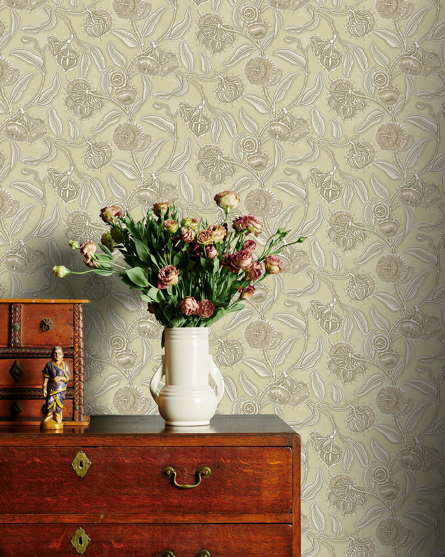 Decorative wallpaper with floral pattern, wooden dresser, and vase with flowers.