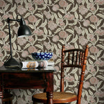 Room interior with a wooden table, chair, and lamp against a brown and pink floral-patterned wall.