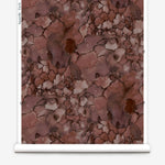 Partially unrolled wallpaper yardage in a watercolor textural print in shades of red, gray and black.