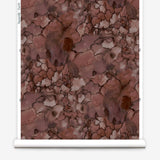 Partially unrolled wallpaper yardage in a watercolor textural print in shades of red, gray and black.