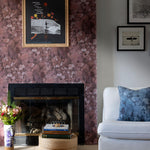 A maximalist living room tableau with a statement wall papered in a watercolor textural print in red, gray and black.
