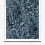 Partially unrolled wallpaper yardage in a watercolor textural print in shades of blue, navy and black.