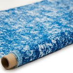 Partially unrolled fabric in an organic crumpled texture in navy on a cream field.