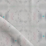 Detail of draped fabric yardage in a repeating ink blot print in shades of gray with turquoise and pink accents.