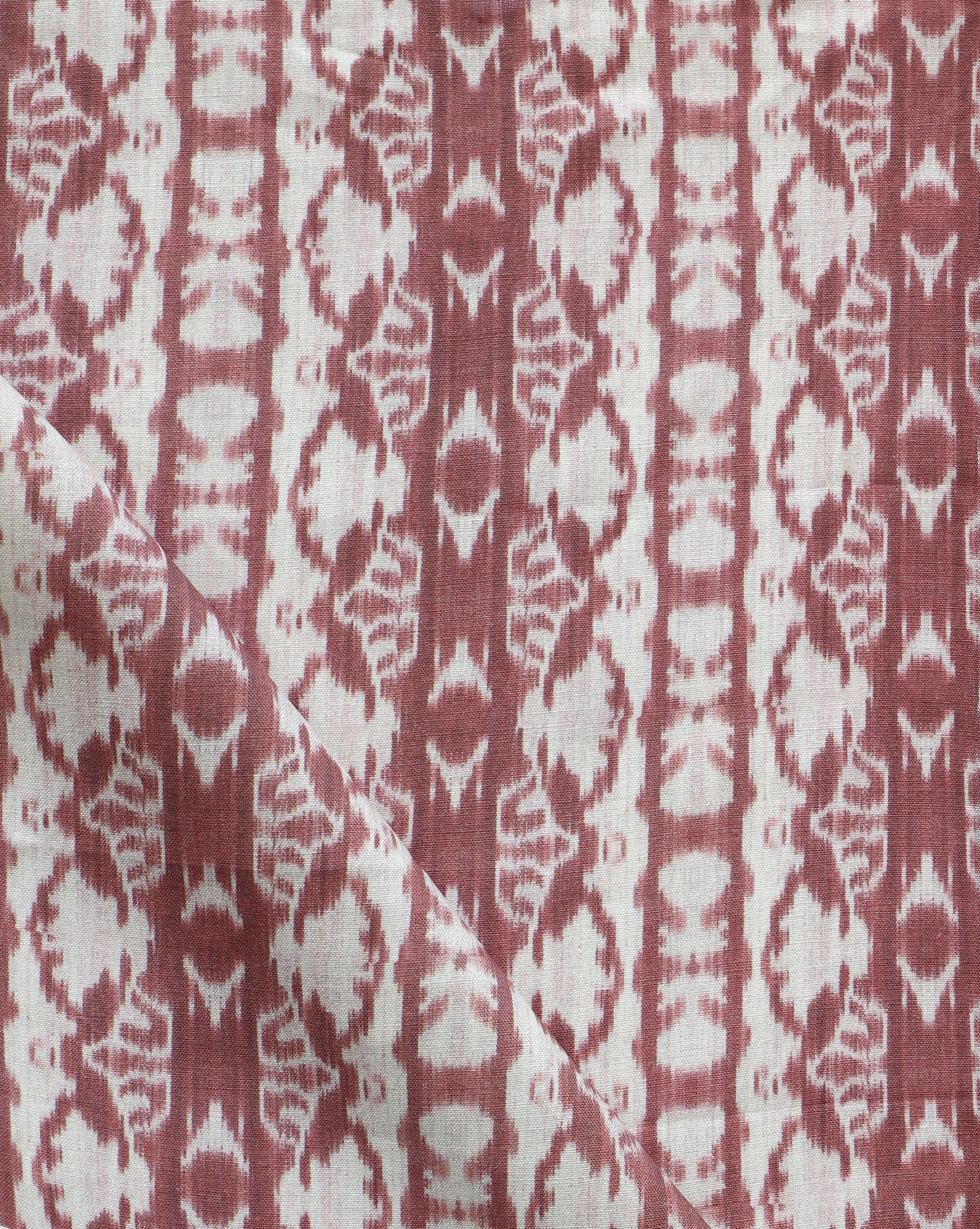 Detail of draped fabric yardage in a watercolor ikat stripe print in shades of white on a red field.