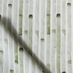 Detail of draped fabric in a painterly stripe print in olive on a white field.