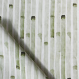 Detail of draped fabric in a painterly stripe print in olive on a white field.