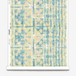 Partially unrolled wallpaper yardage in a watercolor dyed grid print in mottled yellow, blue and white.