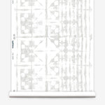 Partially unrolled wallpaper yardage in a watercolor dyed grid print in mottled white and gray.