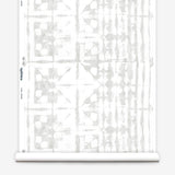 Partially unrolled wallpaper yardage in a watercolor dyed grid print in mottled white and gray.