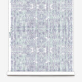 Partially unrolled wallpaper yardage in a watercolor dyed grid print in mottled purple and turquoise.